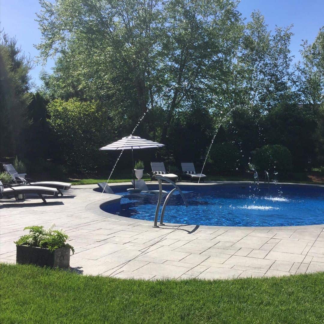 Curved Pool Deck With Integrated Fountains Creates A Refreshing Backyard