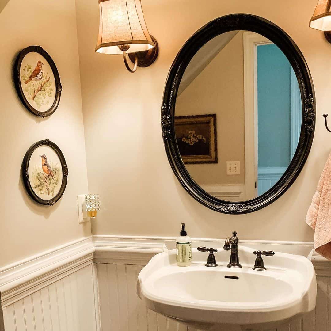 Oval Mirror with Ornate Black Frame Above Pedestal Sink
