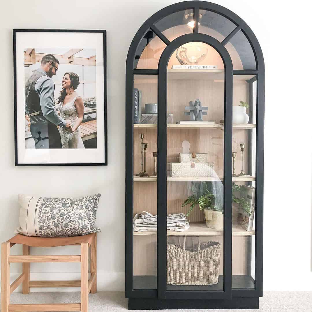 Arched Cabinet With Glass Panes Highlights Brass Candlesticks