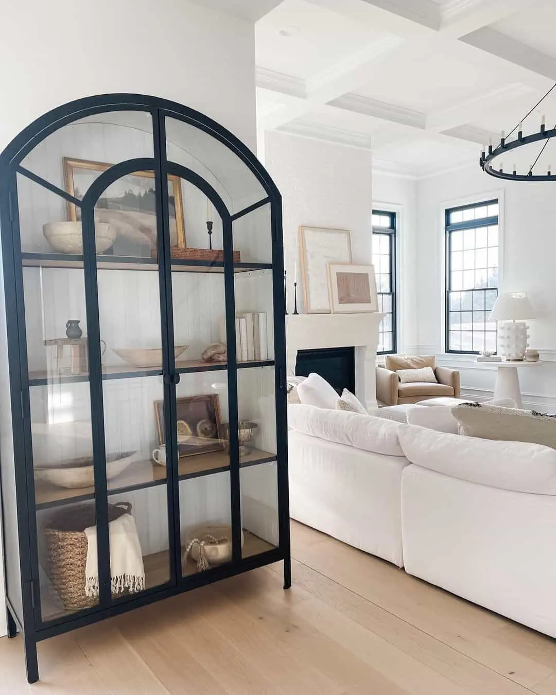 Arched Display Cabinet with Black Metal Frame Holds Varied Decor
