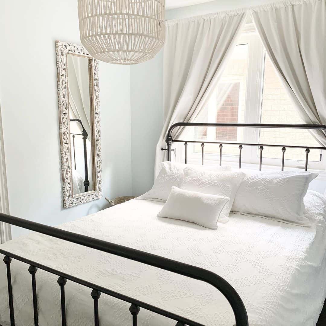 Ornate Carved Mirror Adds a Vintage Touch Above the Bed