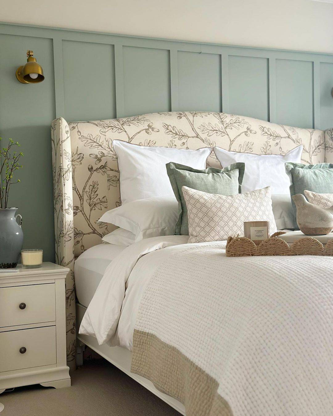 Paneled Sage Green Walls Frame a Botanical Headboard