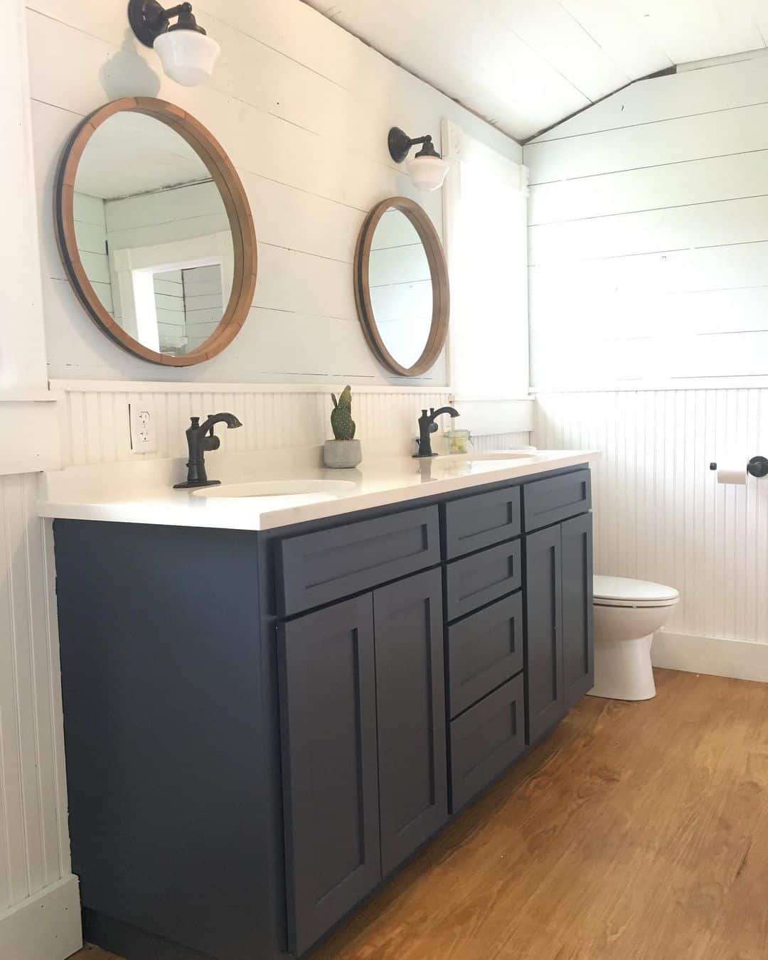 Oval Wood Mirrors Add Natural Warmth Above Dark Vanity