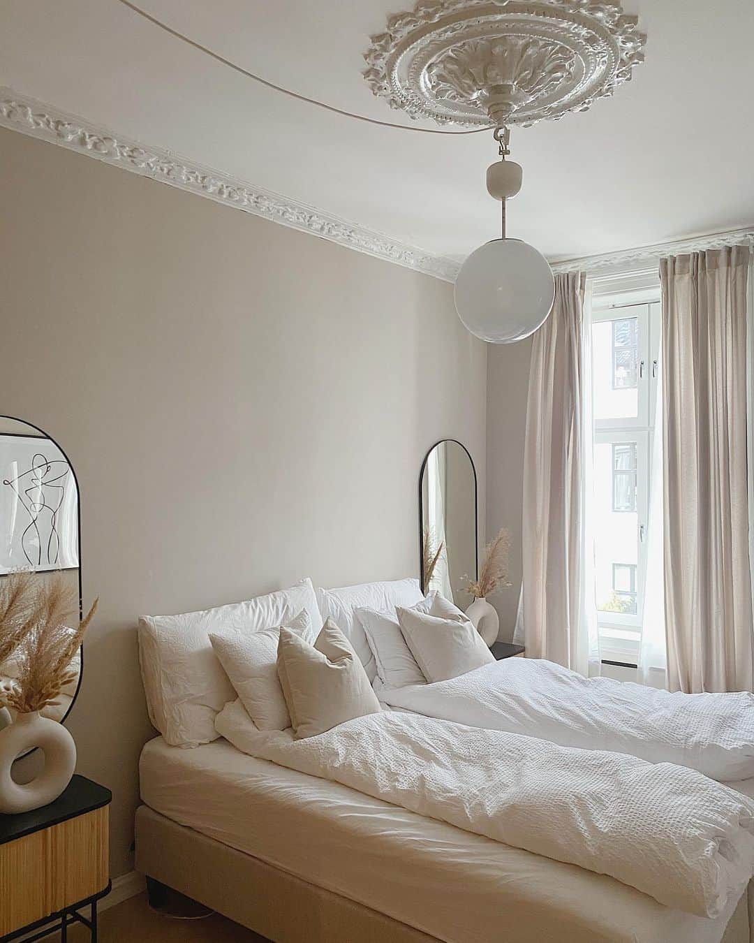 Tall Oval Mirrors Frame the Bedside Tables