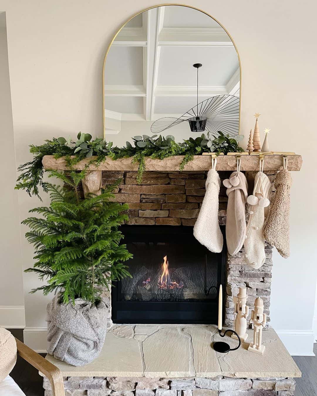Stone Fireplace Mantel Holds Layered Greenery and Festive Stockings