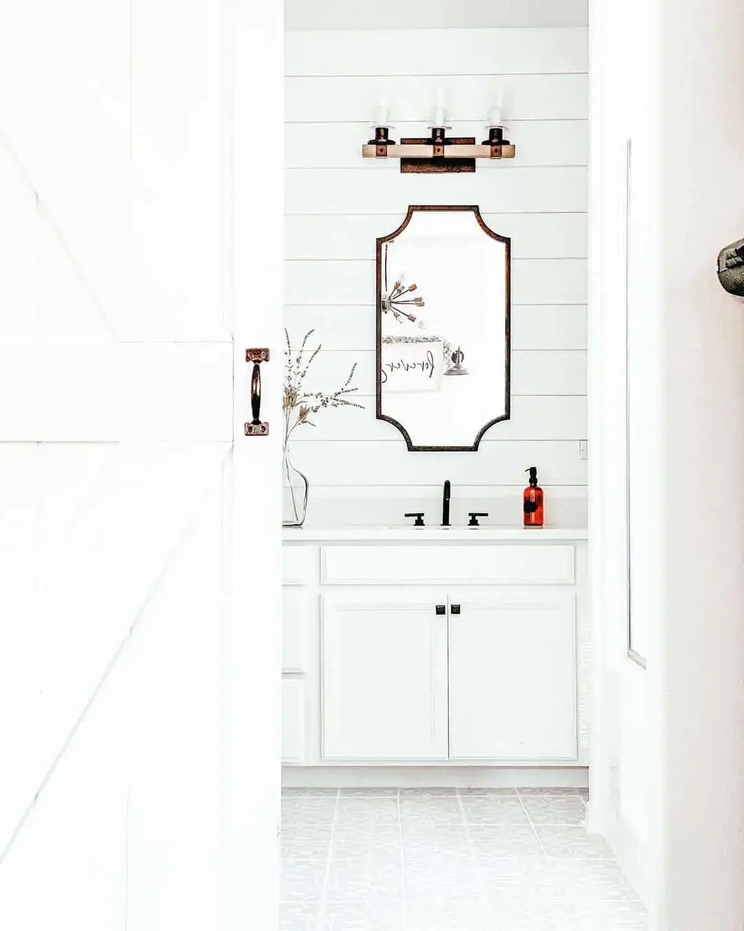Ornate Mirror Frames a Trio of Industrial-Style Vanity Lights