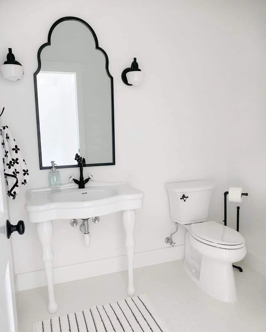 Scalloped Black Mirror Frames a Pedestal Sink