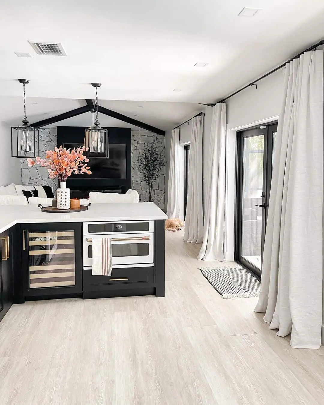 Floor-to-ceiling curtains soften the modern kitchen with their flowing white fabric