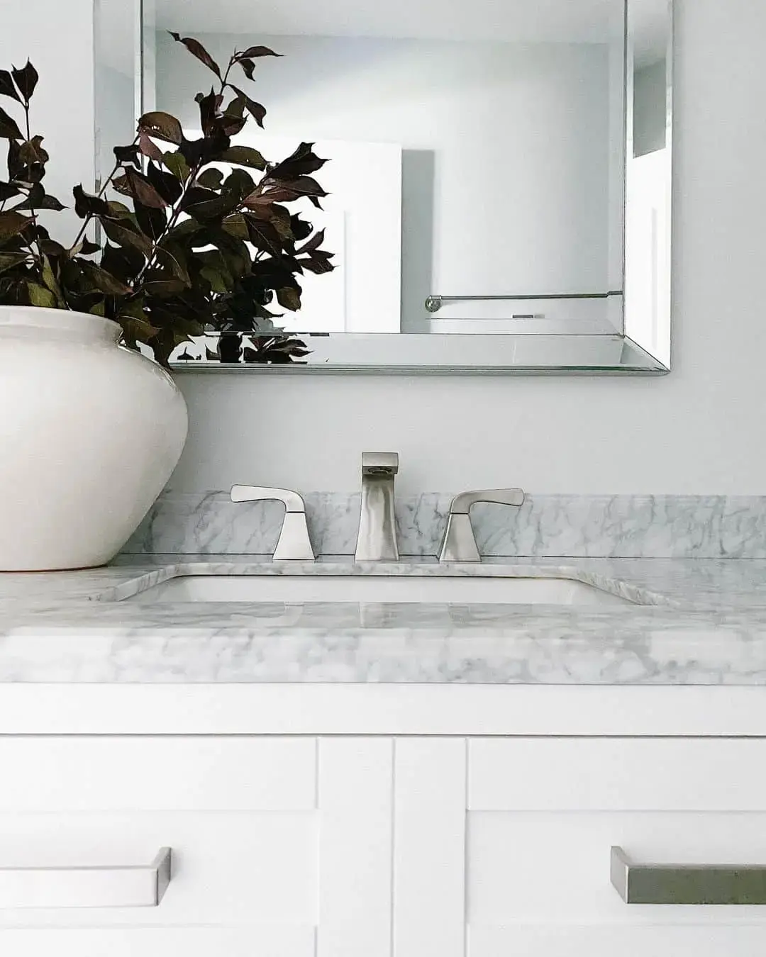 Marble Vanity With Angular Faucet and Dark Greenery