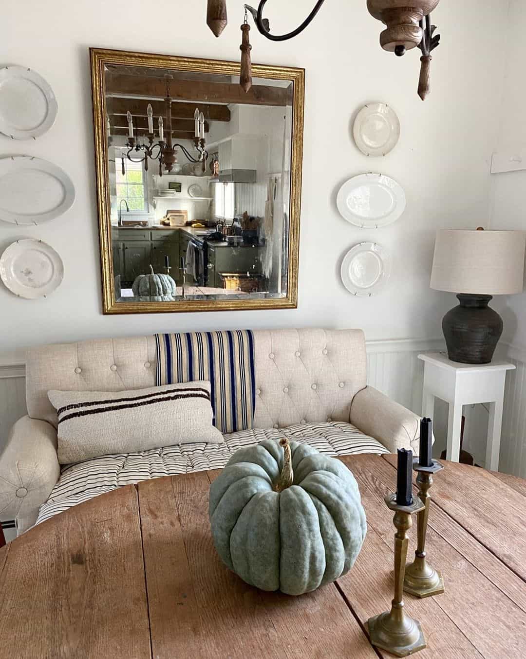 Gilded Mirror Reflects Kitchen Scene Above Tufted Sofa