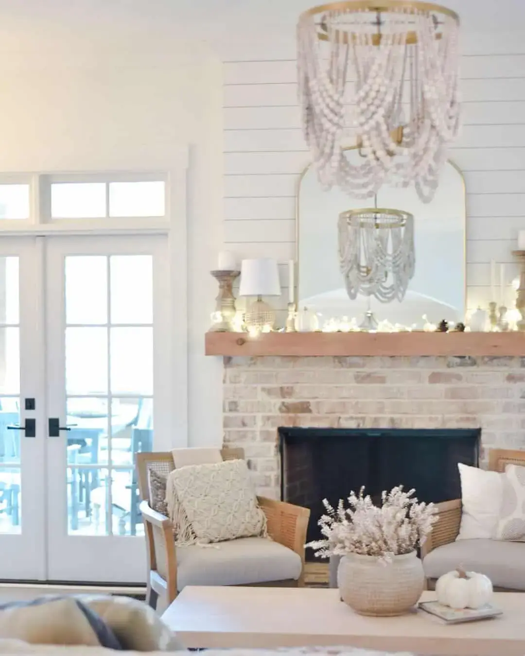 Arched Gold Mirror Reflects Beaded Chandelier Above Mantel