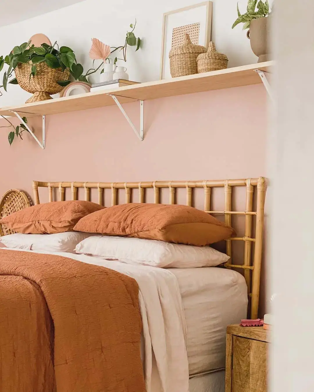 Rattan headboard contrasts with pink walls