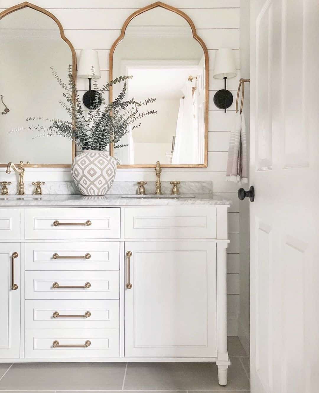 Arched Gold Mirrors Frame Sconces Above Double Vanity