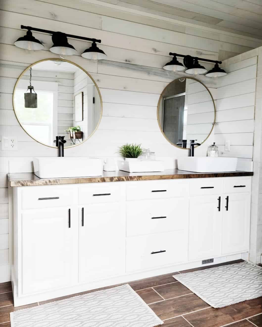 Black Farmhouse Sconces Above Round Gold Mirrors