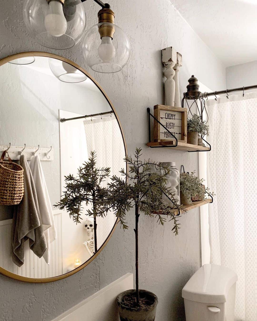 Clear Glass Globe Lights With Brass Accents Above a Round Mirror