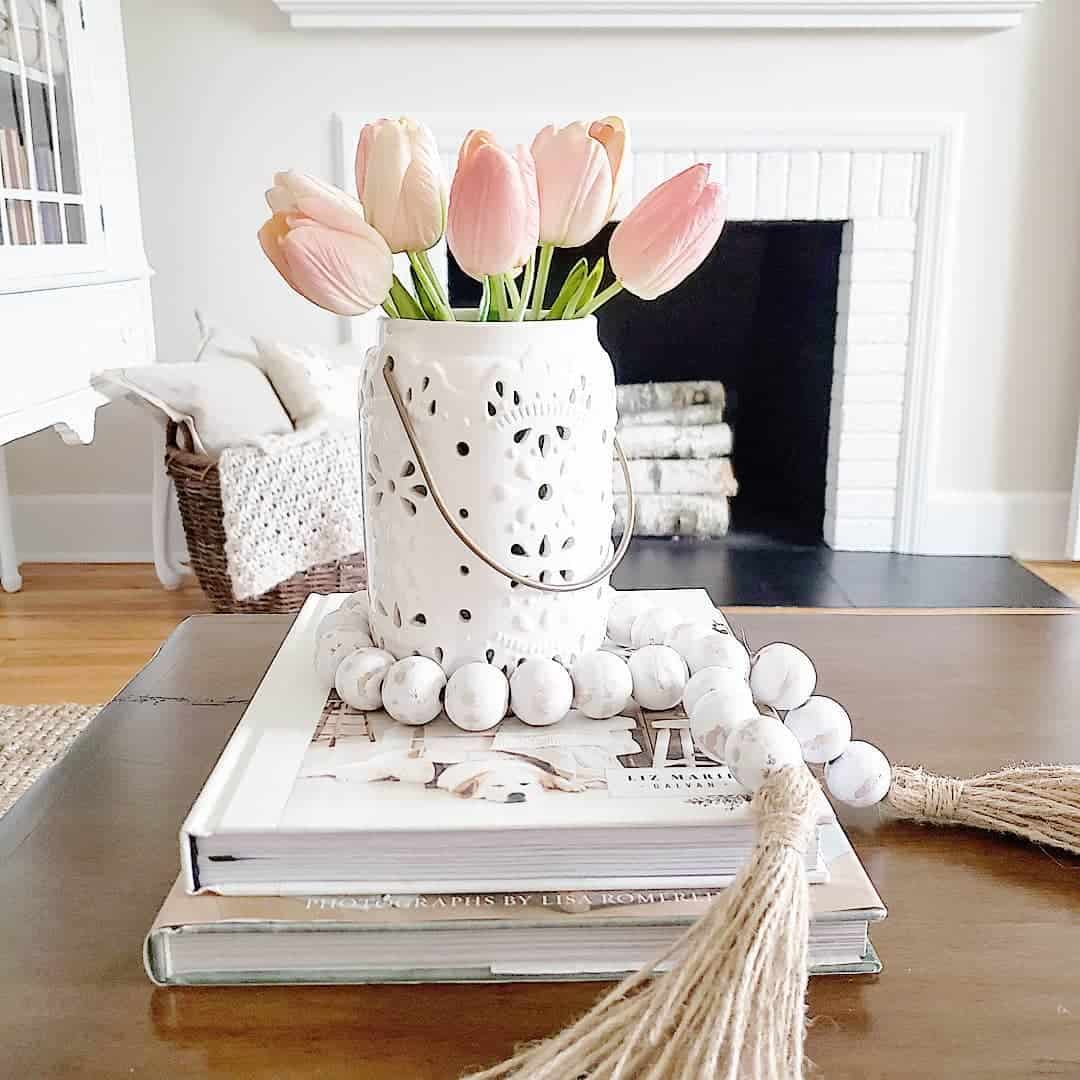 White lantern with cutout details holds a bouquet of pink tulips