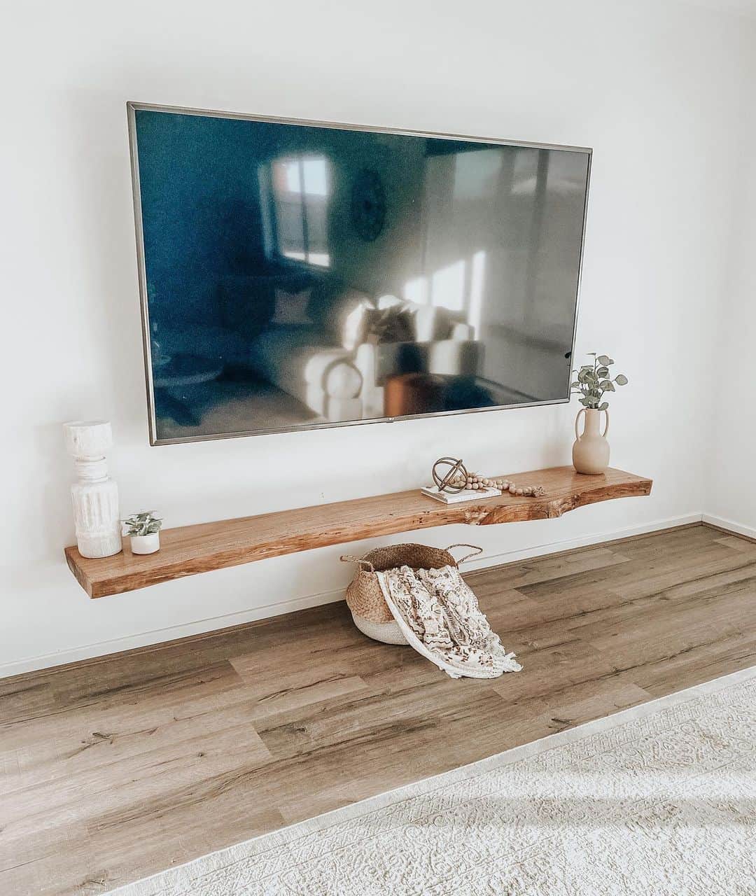 Live-Edge Floating Shelf Holds Decor Below Wall-Mounted TV