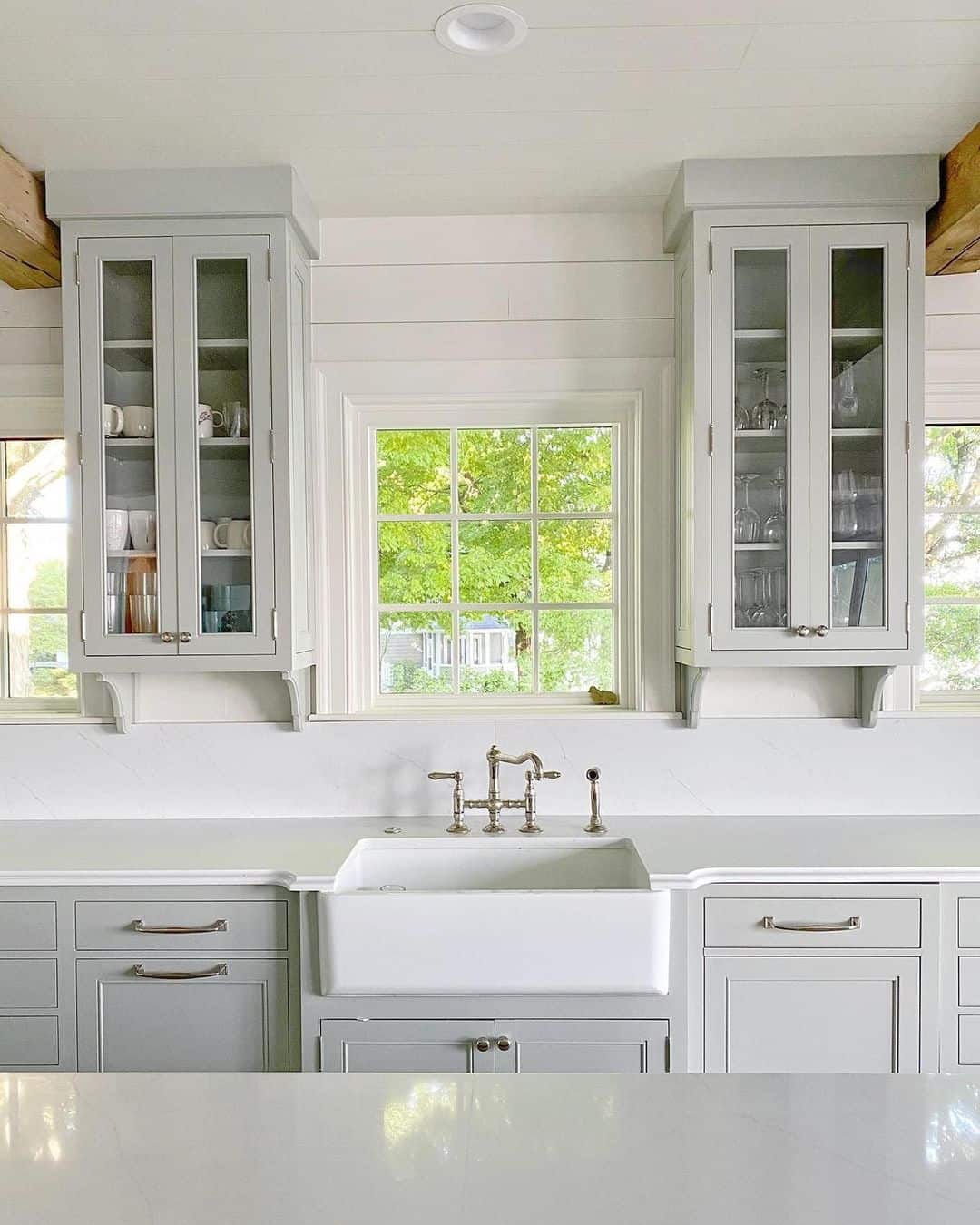 Frame a Windowed Kitchen Scene with Light Gray Glass-Front Cabinets